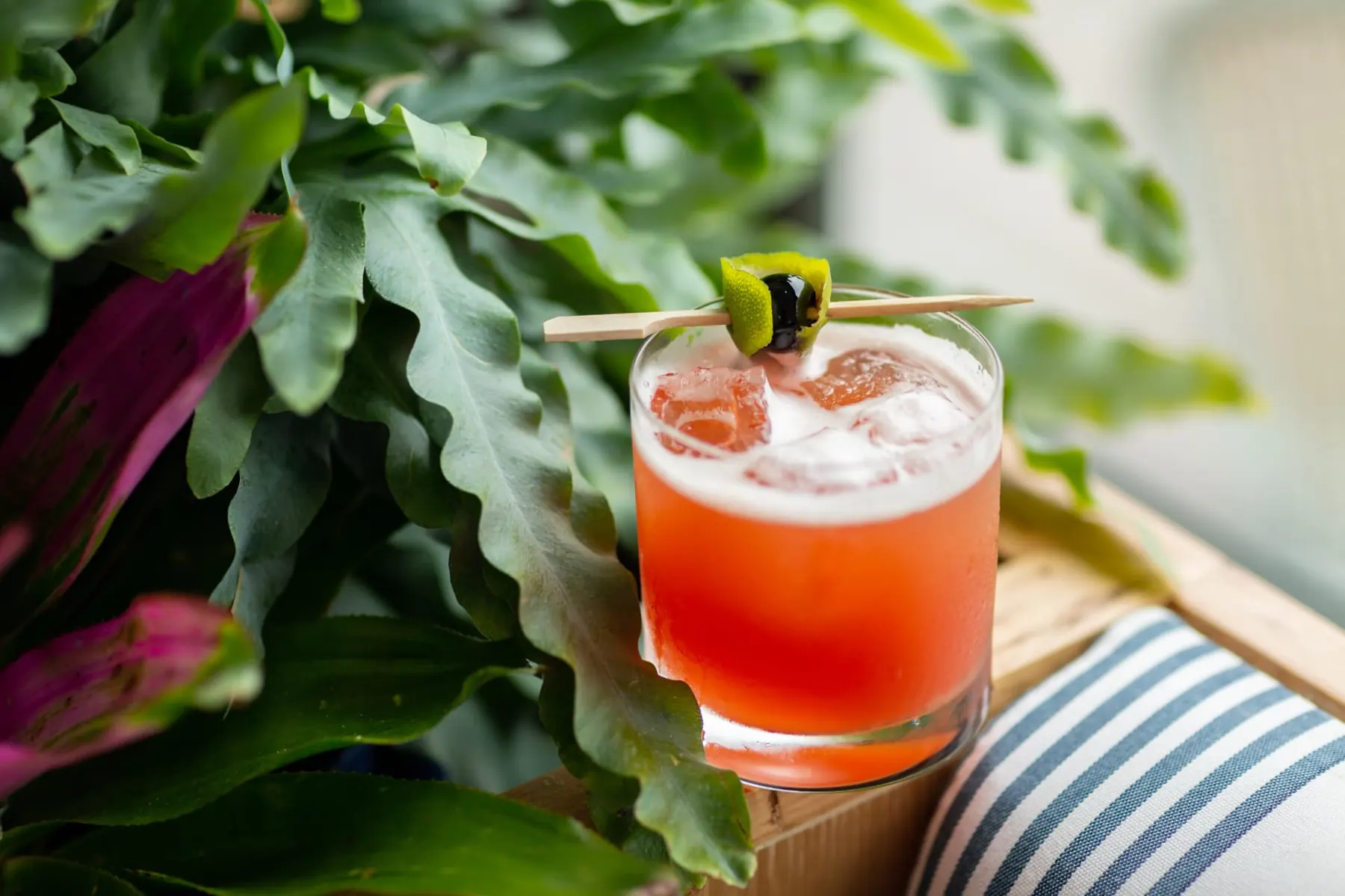 A red craft cocktail with lime garnish at Pendant